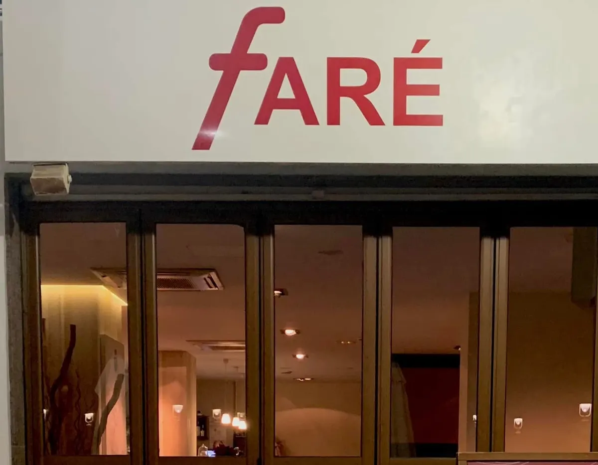 Nuestra fachada de noche, con el rótulo rojo de Faré sobre las puertas de cristal